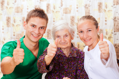 two caregivers and old lady smiling