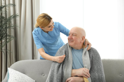 caregiver covering the old man with blanket